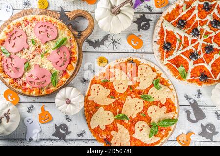 Verschiedene Halloween lustige Pizza. Halloween Party Rezept, Kreative Idee für Halloween Pizza`s mit Schinken und Käse Geister, Monster, Spinnen, weiß Holz Stockfoto